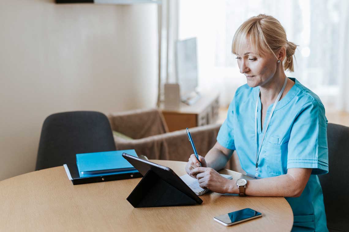 nurse sitting at table using digital tablet