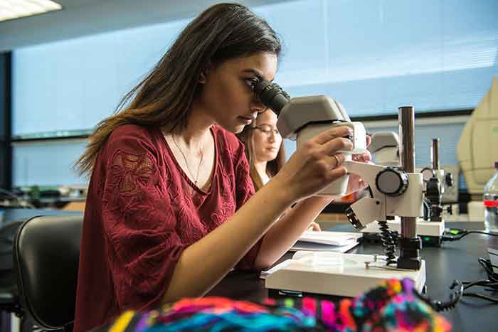 student in science lab using microscope